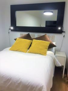 a white bed with yellow pillows and a large mirror at Paz y calma en Madrid centro in Madrid