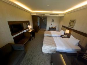 a hotel room with two beds and a flat screen tv at Lancaster Suites Raouche in Beirut