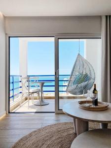 a room with a table and a balcony with the ocean at Front Sea Apartment Quarteira in Quarteira
