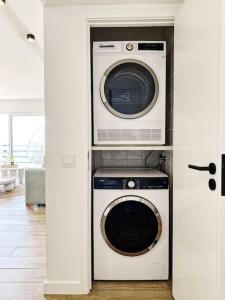 a washer and dryer in a room with a door at Front Sea Apartment Quarteira in Quarteira