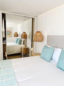 a bedroom with a large white bed and a mirror at Front Sea Apartment Quarteira in Quarteira