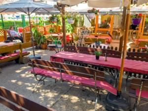 ein Restaurant mit Bänken, Tischen und Sonnenschirmen in der Unterkunft Alt Wehlheiden in Kassel
