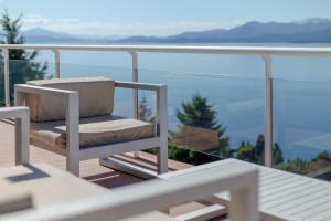 a chair on a balcony with a view of the ocean at Luxury Lake Views Apartments By Apartments Bariloche in San Carlos de Bariloche