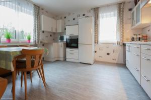 una cocina con electrodomésticos blancos y una mesa con sillas. en Privat-Pension-Doemens en Aquisgrán