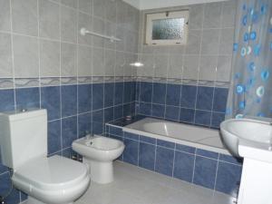 a blue tiled bathroom with a toilet and a sink at Casa Katarina in Luz