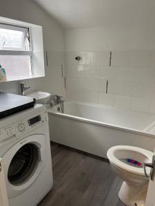 a bathroom with a washing machine and a toilet at Big house with garden in Gillingham