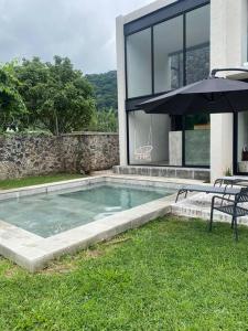 una piscina con sombrilla junto a una casa en Casa Aurora (completamente nueva) en Tepoztlán
