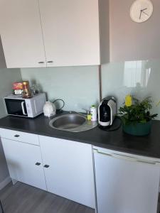 a kitchen with a sink and a microwave at Apartament KORNER Chełmońskiego Śrem in Śrem
