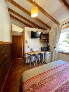 1 dormitorio con 1 cama y cocina con mesa en Cabañas Fischer SpA, en Niebla