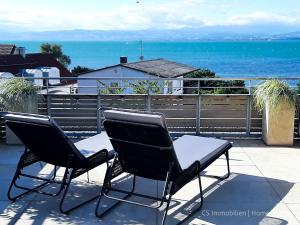 two chairs and a table on a patio overlooking the ocean at Designerloft See in Immenstaad am Bodensee