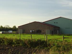 un granero grande en un campo junto a una valla en Kustverhuur, Oude manege Nieuwvliet, Nieuwvliet 3 - 9, en Nieuwvliet