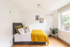 - une chambre blanche avec un lit et une couverture jaune dans l'établissement 2 BDR - Entire Flat - Central London, à Londres