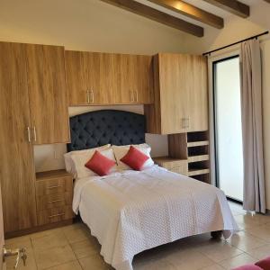 een slaapkamer met een bed met houten kasten en rode kussens bij Casita En Patzcuaro in Pátzcuaro