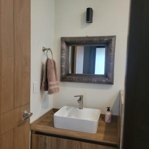 ein Badezimmer mit einem weißen Waschbecken und einem Spiegel in der Unterkunft Casita En Patzcuaro in Pátzcuaro
