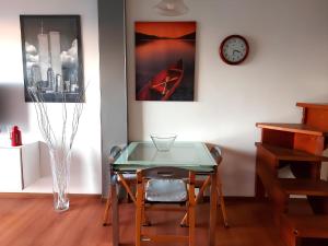 une salle à manger avec une table en verre et une horloge dans l'établissement Garda Panoramic House, à Torri del Benaco