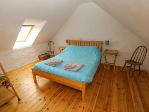 een slaapkamer met een bed met blauwe lakens en houten vloeren bij Workshop in Goodwick
