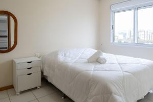 Apto elegante para casal em POA-RS URB1110 في بورتو أليغري: غرفة نوم بيضاء مع سرير ومرآة