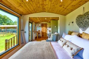 - une chambre avec un lit et une grande fenêtre dans l'établissement Abberley Shepherds Hut - Ockeridge Rural Retreats, à Wichenford