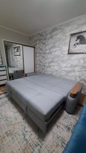 1 dormitorio con 1 cama grande y pared de piedra en 2-х комнатная квартира, en Almaty