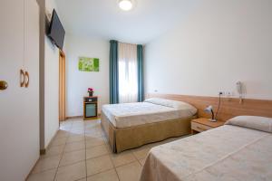 una camera d'albergo con due letti e una televisione di Hotel Ginevra a Lido di Jesolo