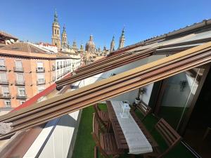 a balcony with a table and chairs on a building at Dos Torres Ático - Solárium Privado en Calle Alfonso I in Zaragoza