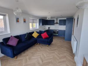 ein Wohnzimmer mit einem blauen Sofa und bunten Kissen in der Unterkunft 13 Cambrian Court in Penmaen-mawr