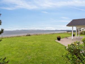a lawn with a gazebo and a view of the ocean at Holiday Home Enwald - 275m from the sea in Djursland and Mols by Interhome in Knebel