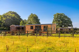 a wooden house in a field with a fence at Abberley Shepherds Hut - Ockeridge Rural Retreats in Wichenford