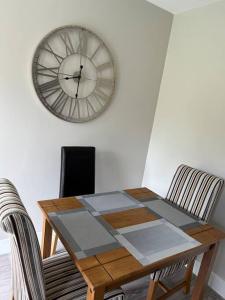 a dining room table with a clock on the wall at Meadow View in Alfreton