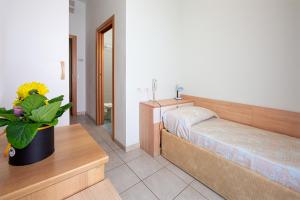 una camera con un letto e un vaso con una pianta di Hotel Ginevra a Lido di Jesolo