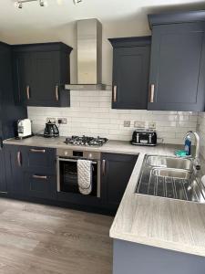 a kitchen with black cabinets and a sink at Meadow View in Alfreton