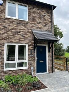 a brick house with a blue door and windows at Meadow View in Alfreton