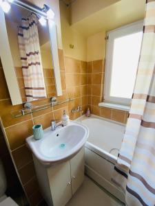 een badkamer met een wastafel, een bad en een raam bij Apartament Luna in Piatra Neamţ
