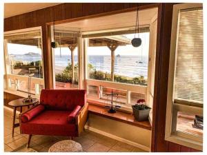 una silla roja sentada en una ventana con vistas al océano en Redwood Coast Beach Front Home California, en Smith River
