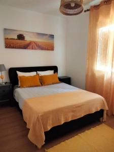 a bedroom with a bed with orange pillows at Casa dos Rosas in Melides