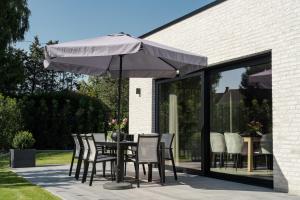 een tafel en stoelen met een parasol op een patio bij Amazing holiday home "Beaunita" with 4 bedrooms and 4 bathrooms in Hamont