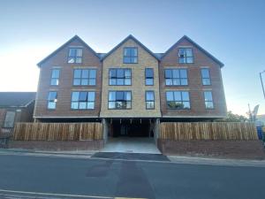 a large brick building with a fence in front of it at Stylish & Spacious Apartment in Royal Tunbridge Wells
