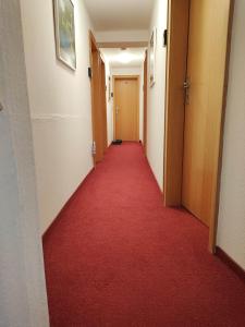 un lungo corridoio con un tappeto rosso in un edificio di Pension Forelle a Forbach