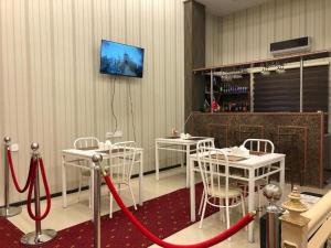 a room with white tables and chairs and a tv on the wall at HOTEL MRT in Mingachevir
