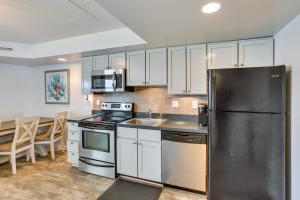 a kitchen with white cabinets and a black refrigerator at Wildwood Crest Condo Rental Walk to Beach! in Wildwood Crest