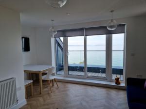 a living room with a large window with a view of the ocean at 13 Cambrian Court in Penmaen-mawr