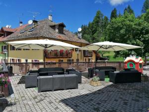 a patio with tables and umbrellas and a playground at Giongo Residence Aparthotel 103 in Lavarone