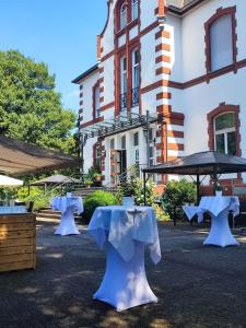 un grupo de mesas y sombrillas frente a un edificio en Villa Sophienhöhe, en Kerpen