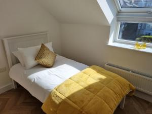 a bedroom with a bed with a yellow blanket and a window at 13 Cambrian Court in Penmaen-mawr