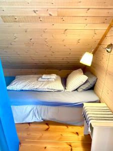 a bed in a cabin with a wooden wall at Skjerping gårdshus, in Lonevåg