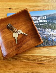 een houten portemonnee met een sleutel bovenop een tijdschrift bij Ferienwohnungen Hexenstieg & Wurmbergblick in Schierke