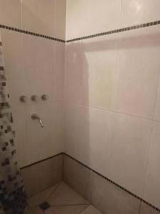 uma casa de banho com um chuveiro com azulejos brancos em Casa de 2 plantas con parque y quincho em Mar del Plata