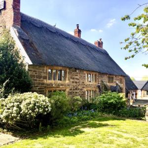 an old stone house with a thatched roof at Hunt House Rooms in Kilsby