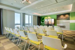 Sala de conferencias con sillas blancas y pantalla de proyección en Citadines Danube Vienna, en Viena