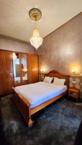 Un dormitorio con una cama grande y una lámpara de araña. en NF Palace Old City Bucharest en Bucarest